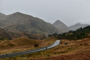 An atmospheric picture of an empty road surrounded by fog and mountains
