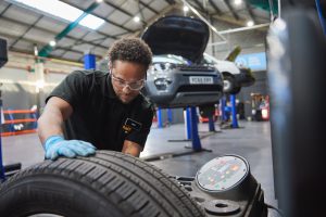 A Halfords expert performing a wheel balance in a garage