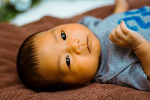Young baby lying face up on a brown fabric